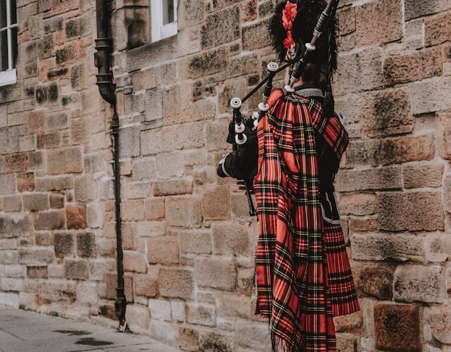 the back of a man playing the bagpipes